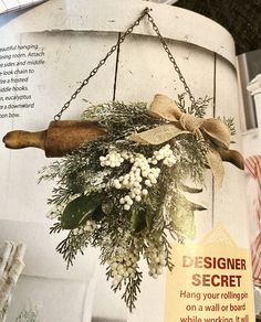 a wreath hanging from the side of a white building with a sign saying designer secret hang your pillar on a wall or door