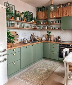 a kitchen filled with lots of green cupboards and counter top space next to a dining room table