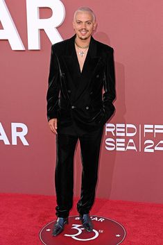 a man in a black suit standing on a red carpet