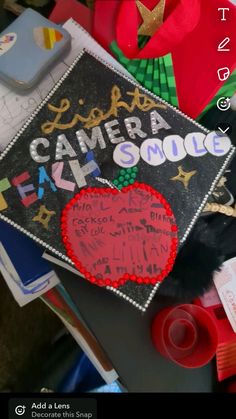 a black and red graduation cap with writing on it, surrounded by other school supplies