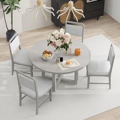 a dining room table and chairs with flowers in vases on the top, next to a white rug