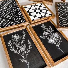 four wooden frames with black and white designs on them, one has flowers in the middle