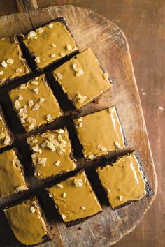 peanut butter brownies on a wooden cutting board with caramel icing and walnuts