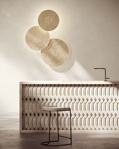 three decorative plates hang on the wall above a table with stools in front of it