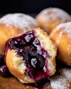 doughnuts with blueberry sauce and powdered sugar are on a cutting board