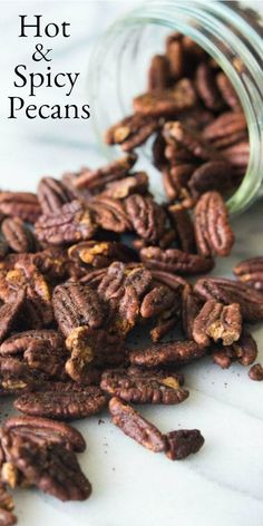 some pecans sitting on top of a table next to a glass jar with the words hot and spicy pecans