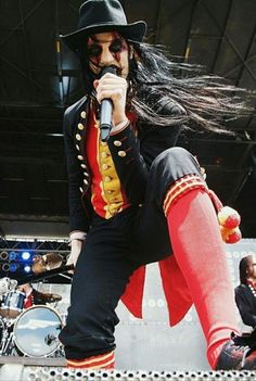 a man with long black hair is performing on stage