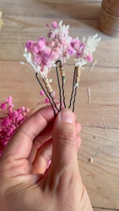 someone is holding some tiny flowers in their hand on the table next to pink and white flowers