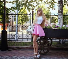 a barbie doll is standing next to a wagon