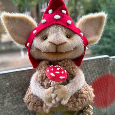 a stuffed animal with a red hat on it's head holding a small mushroom