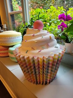 two cupcakes sitting on top of a counter next to potted plants and flowers