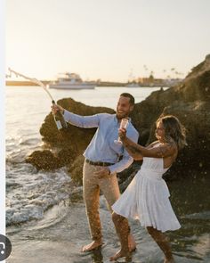 a man and woman are dancing on the beach with their arms around each other as they stand in the water