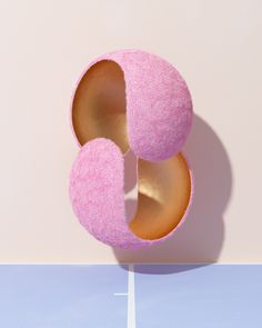 a pink donut sitting on top of a blue table next to a white wall