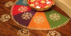 a bowl filled with flowers sitting on top of a wooden floor next to a rug