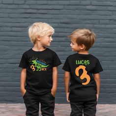 two young boys standing next to each other wearing black shirts with the number three on them