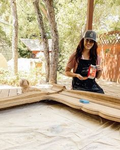 a woman sitting on top of a wooden floor next to a tree filled with leaves