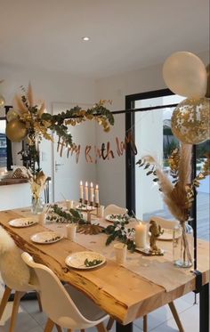 a wooden table topped with white plates and gold decorations next to tall candlesticks