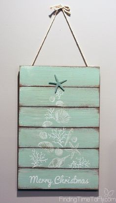 a wooden sign hanging on the wall with a starfish and shells painted on it