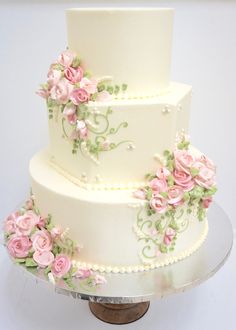 a three tiered white cake with pink flowers on it