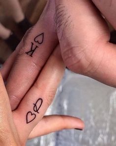 two people holding hands with tattoos on their fingers and one has the word love written on it