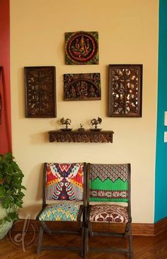 two colorful chairs sitting next to each other in front of a wall with pictures on it