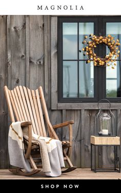 a wooden rocking chair sitting on top of a wooden porch next to a wreath and window