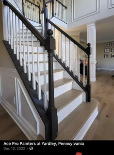 a white staircase with black handrails and wood flooring in a home's entryway