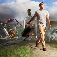 a man walking down a dirt road next to a bottle filled with alcohol and other items