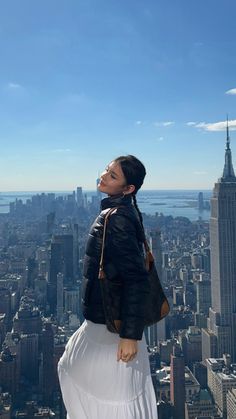 a woman standing on top of a tall building looking at the cityscape in new york