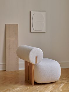 a white chair sitting on top of a hard wood floor next to a wooden block