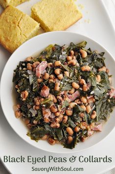 a white plate topped with black eyed peas and collard greens next to cornbreads