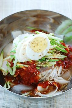 a bowl filled with noodles, meat and an egg on top of it's side