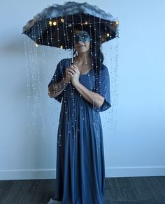 a woman in a blue dress holding an umbrella with rain coming out of the top