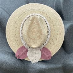 a straw hat with pink and white tassels sits on top of a blue chair