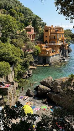 people are on the beach in front of an orange building with many balconies