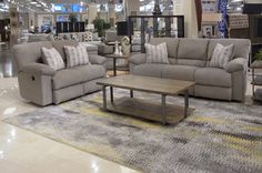 a living room filled with lots of furniture in a store next to a couch and loveseat