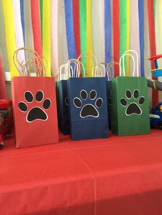 three bags with paw prints on them are sitting on a table in front of colorful streamers