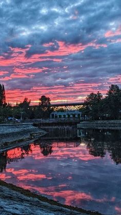 the sky is pink and blue with clouds reflecting in the water