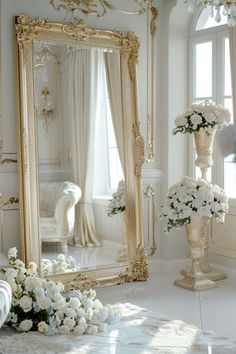 a large mirror sitting on top of a floor next to a vase filled with flowers