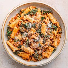 a bowl filled with pasta and sauce covered in parmesan cheese