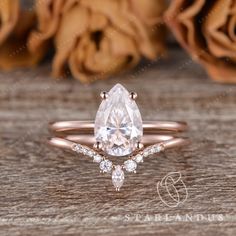 a rose gold ring with a pear shaped diamond and two small diamonds on the band