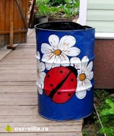 a painted ladybug and daisies on a blue trash can