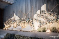 an elaborately decorated stage with white chairs and flowers