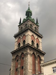 a tall brick tower with a clock on it's side under a cloudy sky