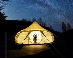 a person standing in front of a tent under the stars