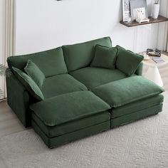 a large green couch sitting on top of a white rug in a living room next to a window