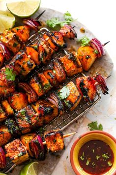 chicken skewers with cilantro, onions and limes on a tray