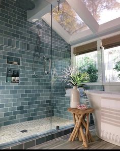 a bath room with a stand up shower next to a tub and a plant in a vase