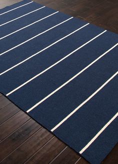 a blue area rug with white lines on the floor in front of a wooden wall