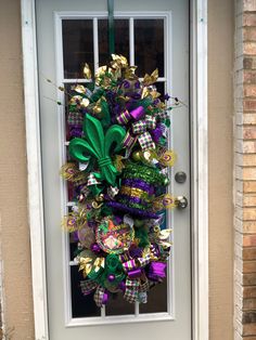 a green and purple wreath is hanging on the front door to a house that's decorated for st patrick's day